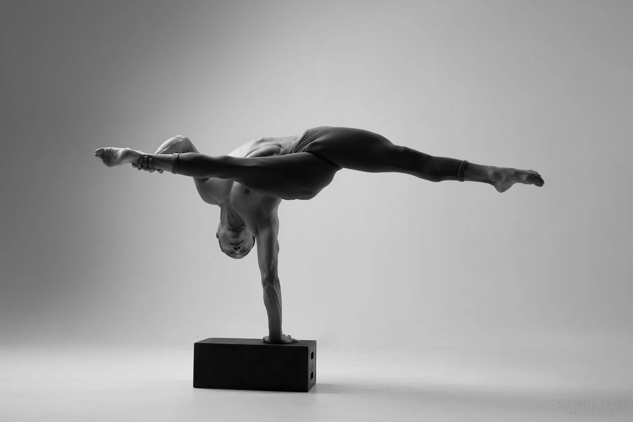 Ochir holding a one-arm straddle balance in the studio
